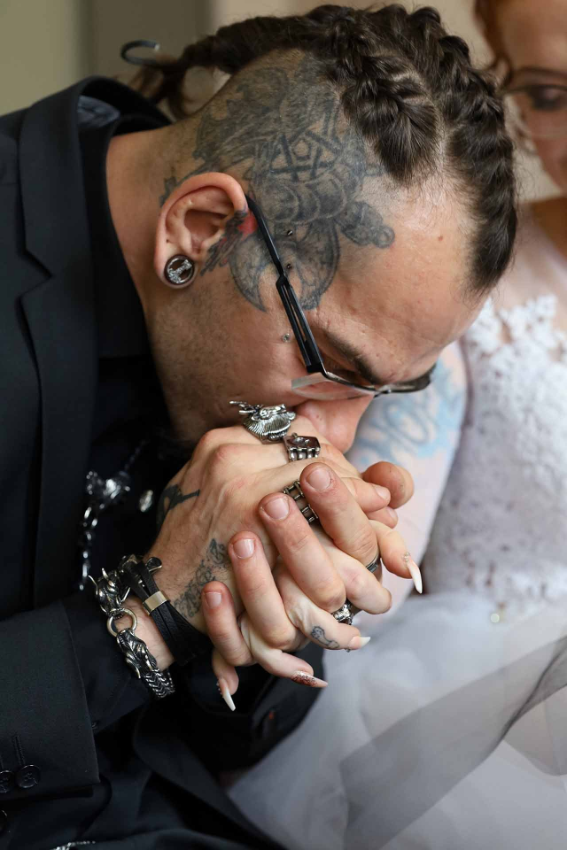 Ein Mann mit einer Tätowierung auf dem Kopf hält die Hand einer Frau.