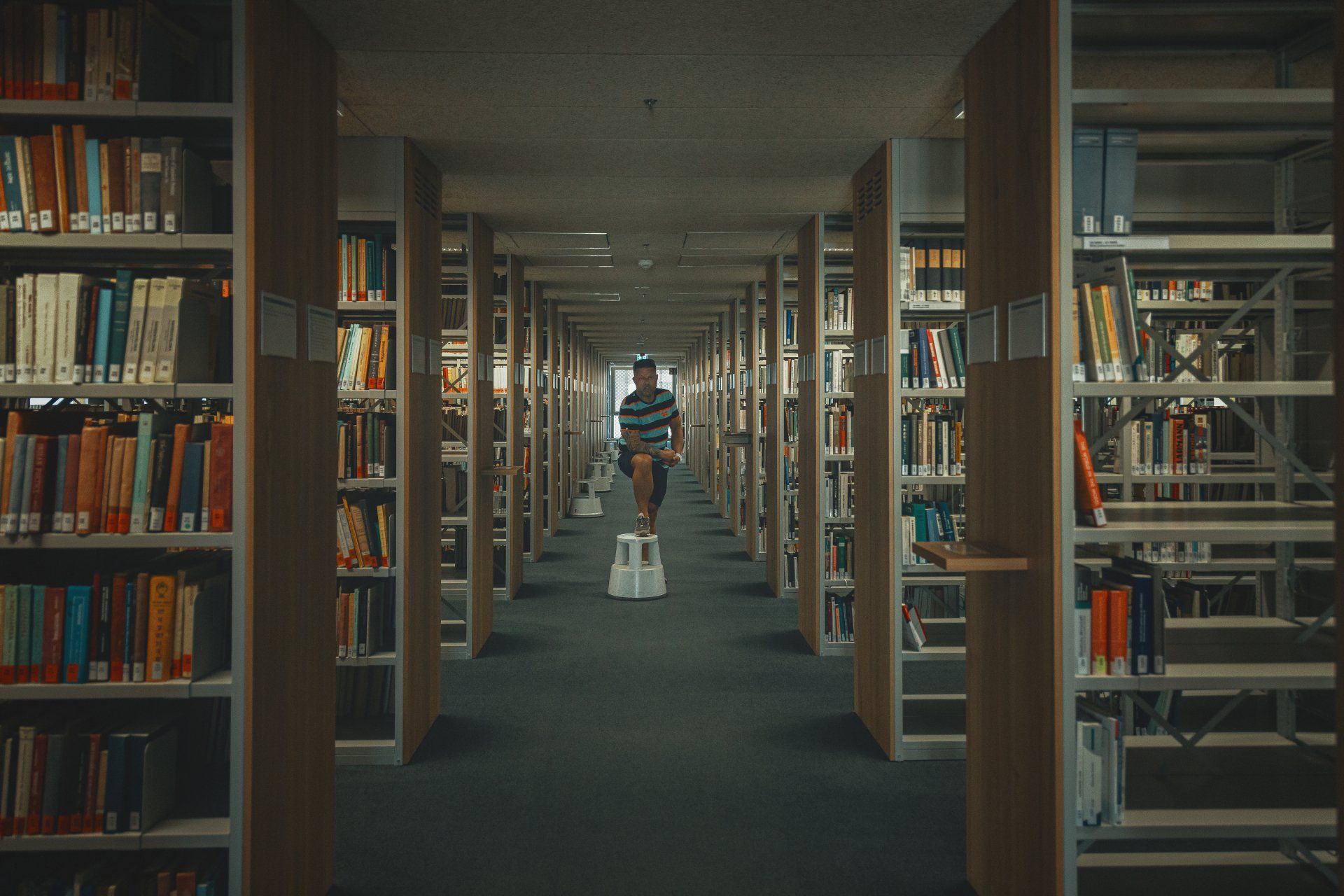 Ein Mann geht durch eine Bibliothek voller Bücher.