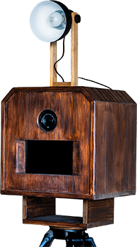 Fotoautomat aus Holz mit eingebautem Licht, schwarzem Kameraobjektiv und Stativfuß.