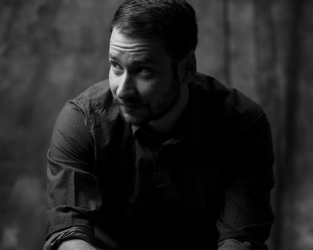 Ein Schwarzweißfoto eines Mannes mit Bart, der Hemd und Krawatte trägt.