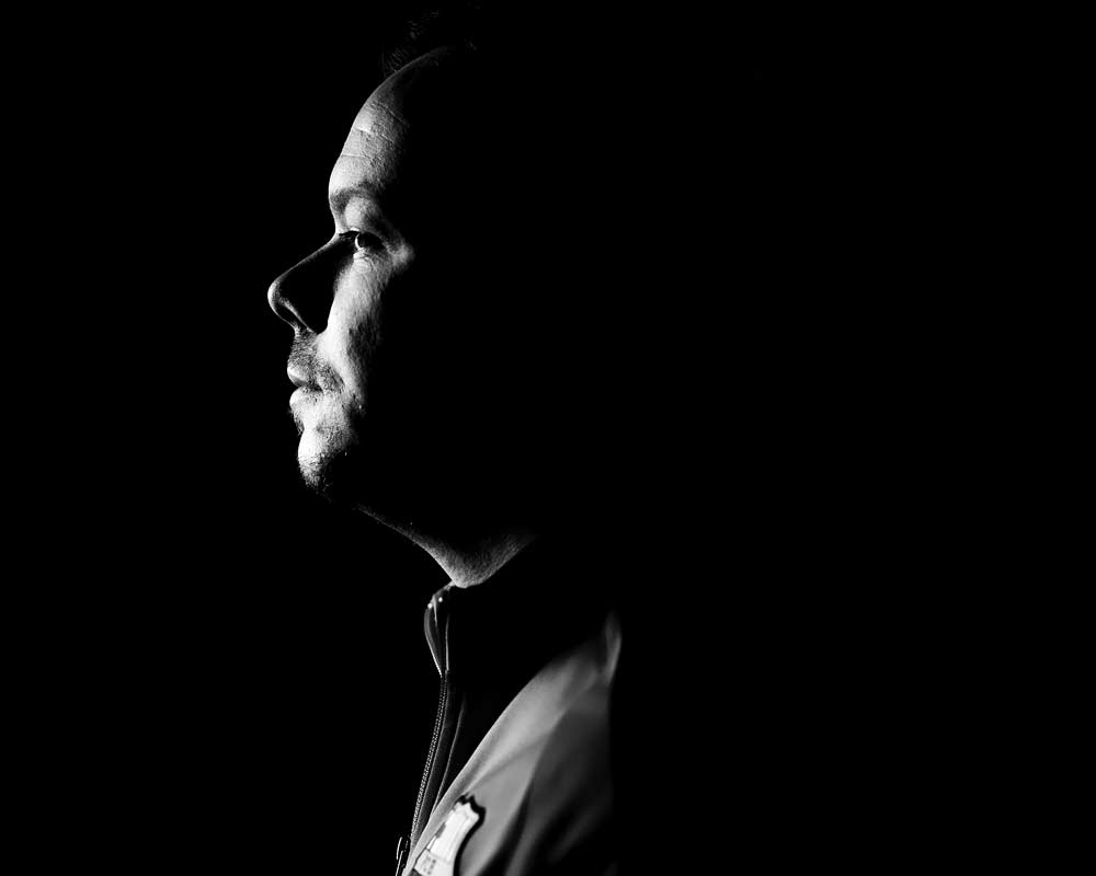 Ein Schwarzweißfoto des Gesichts eines Mannes im Dunkeln.