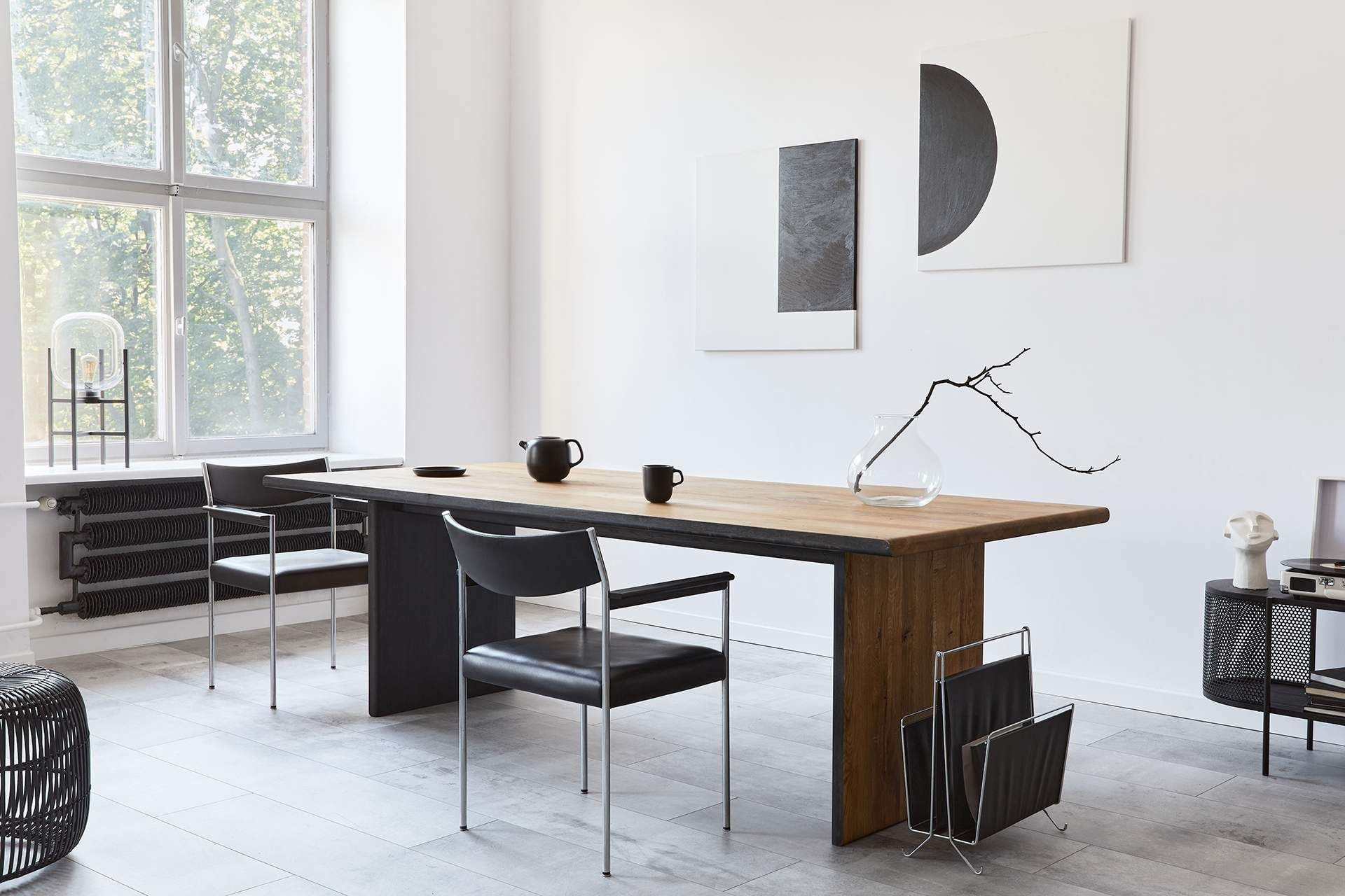 Dining room with a long wooden table, chairs, and abstract artwork.
