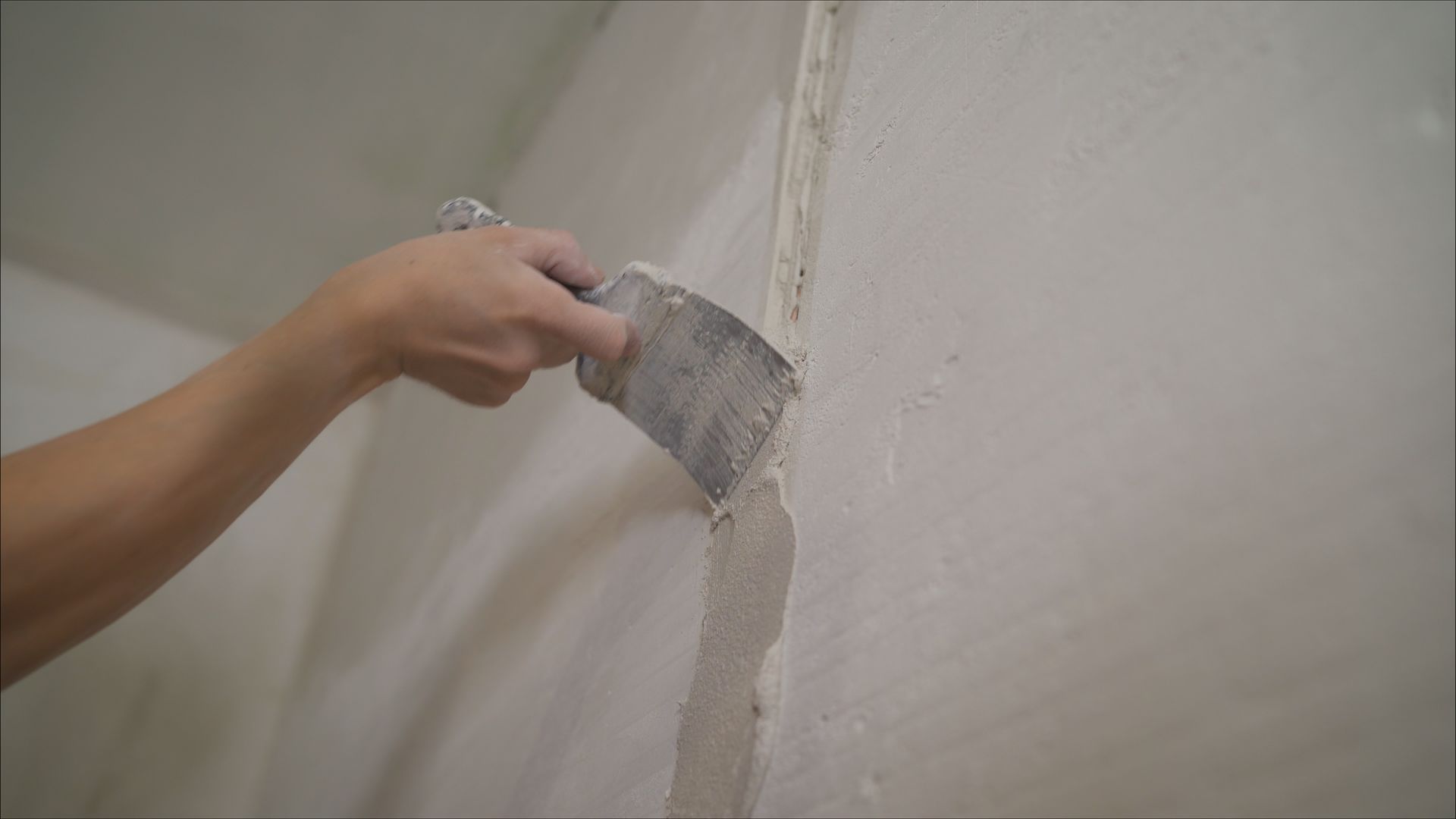 Construction worker in hard hat paints wall with roller.