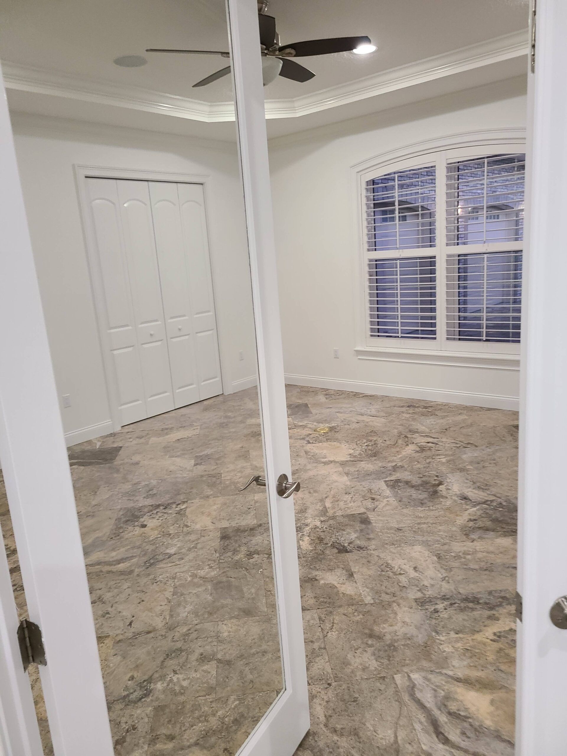 A bedroom with a ceiling fan and a mirror.