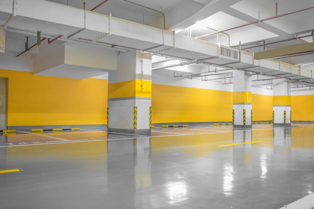 An empty parking garage with yellow walls and a concrete floor.