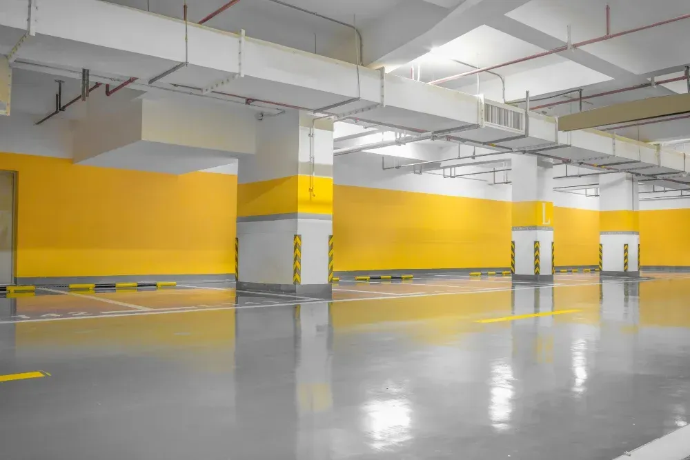 An empty parking garage with yellow walls and a gray floor.