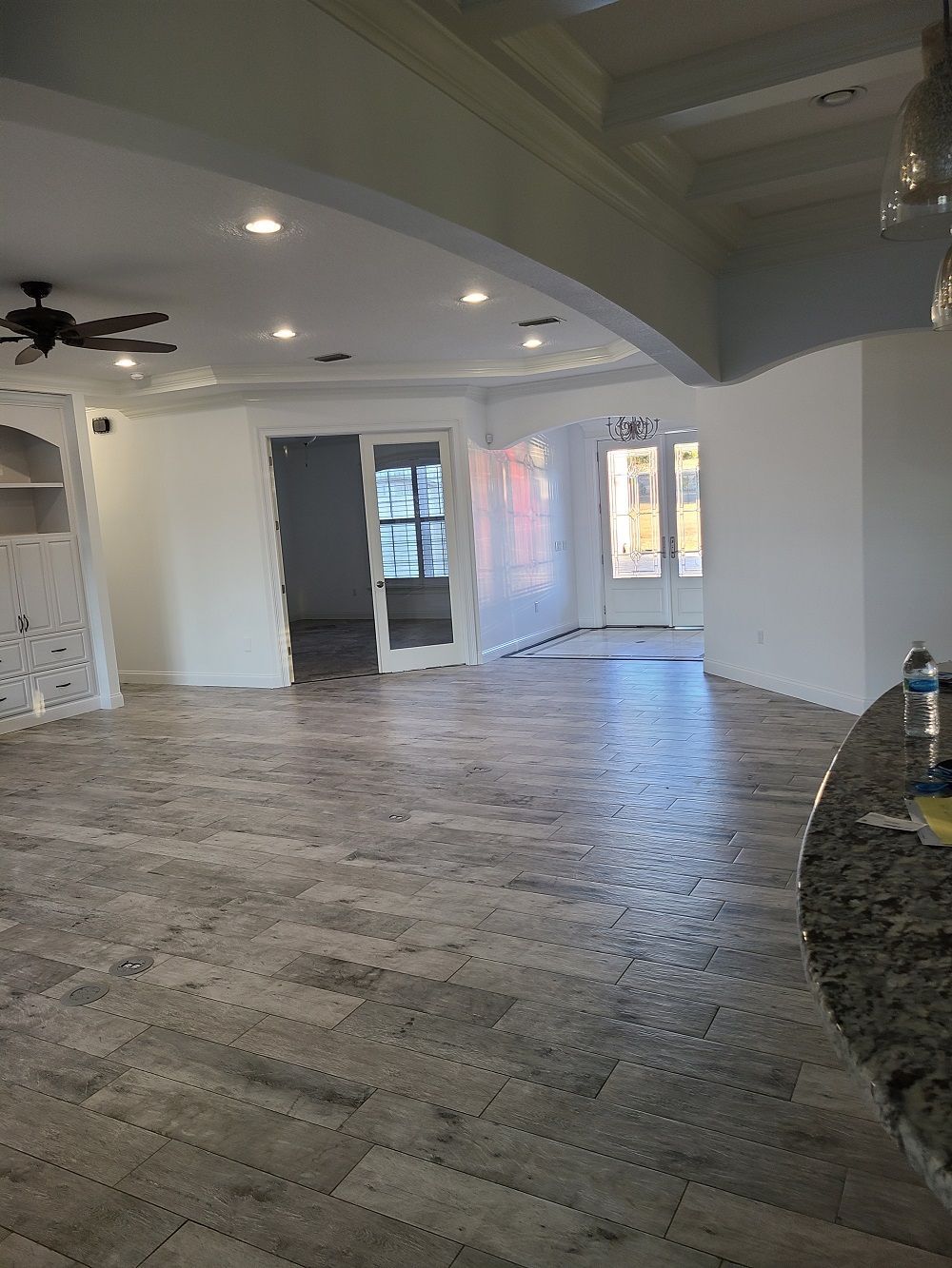 A large empty room with a ceiling fan and sliding glass doors.