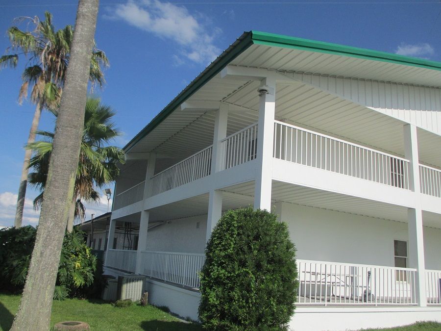 A white house with a green roof and a balcony