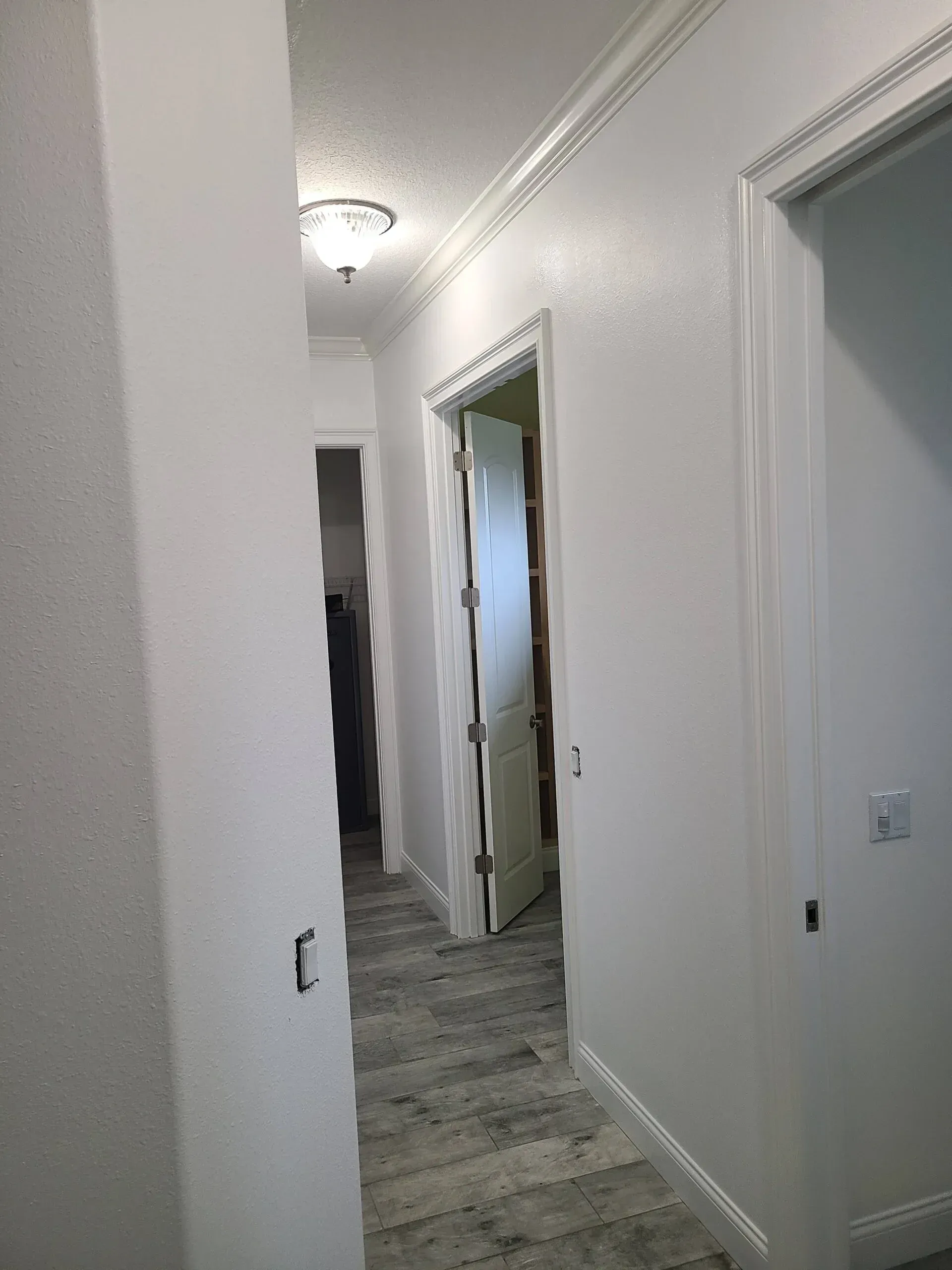 A hallway with white walls and a door in a house.