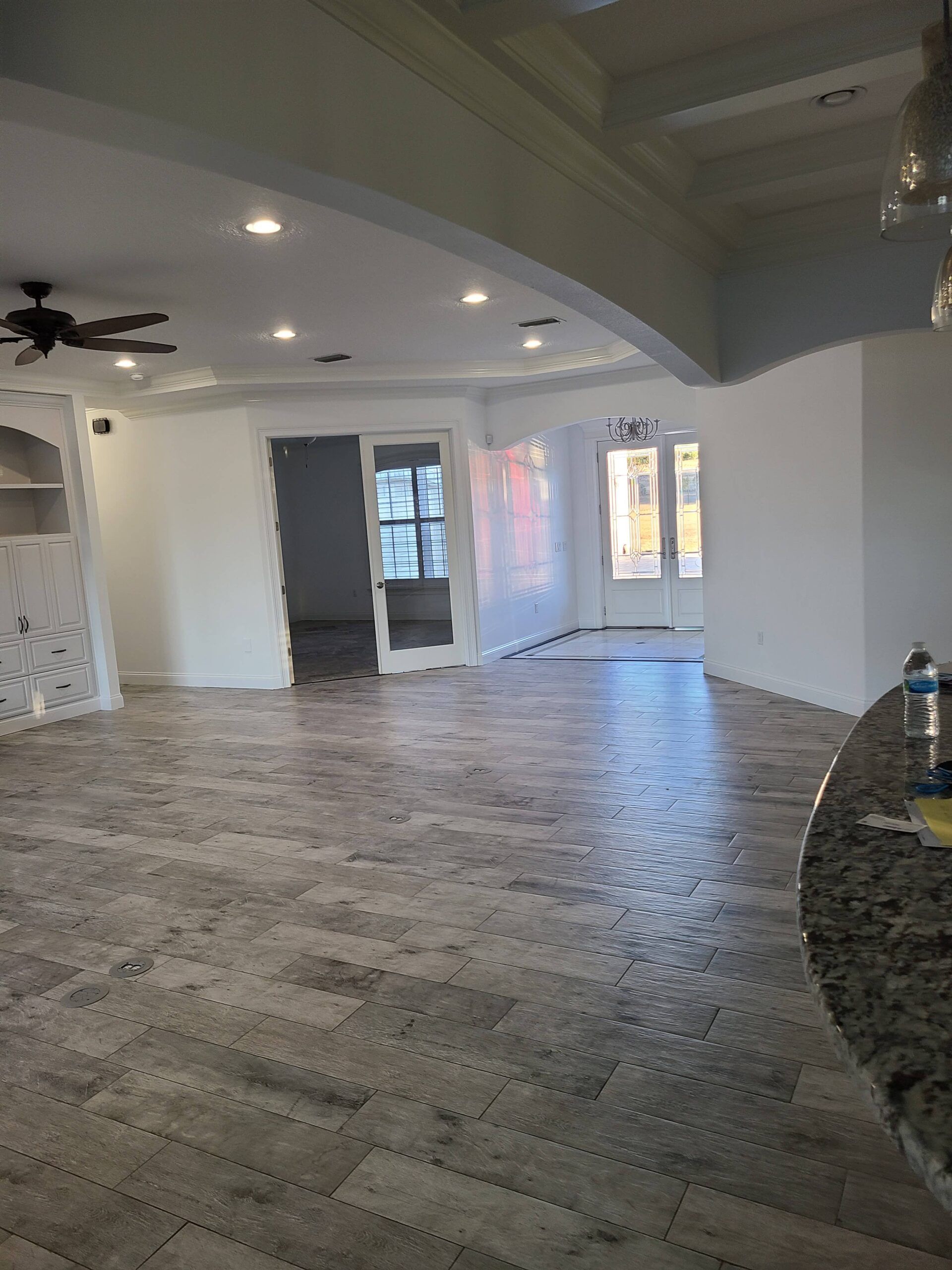 A large empty room with a ceiling fan and sliding glass doors.