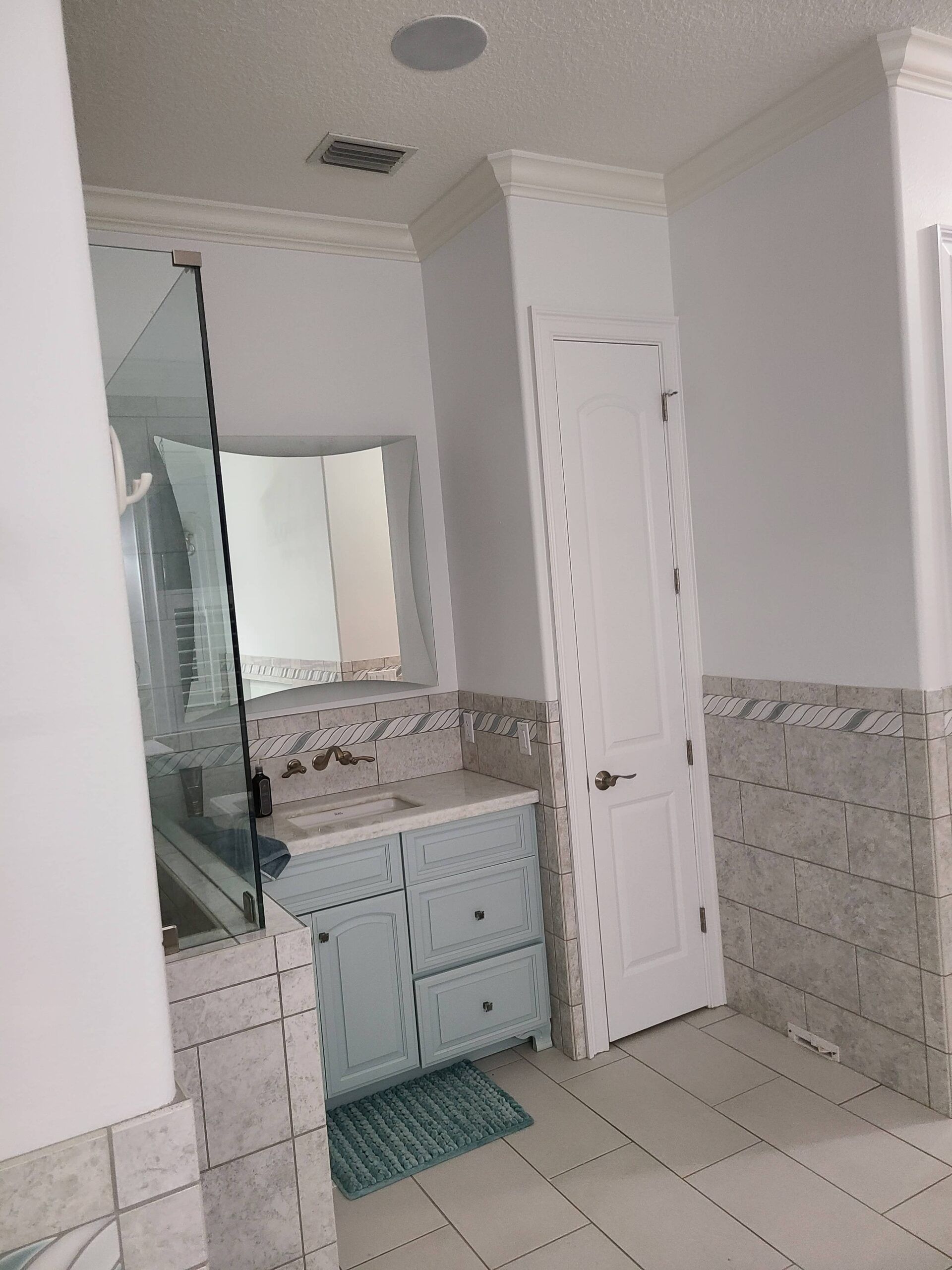 A bathroom with a sink , mirror and door