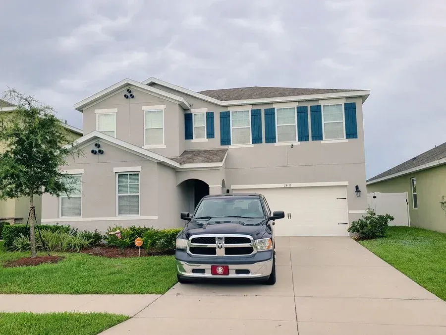 A dodge ram truck is parked in front of a large house.