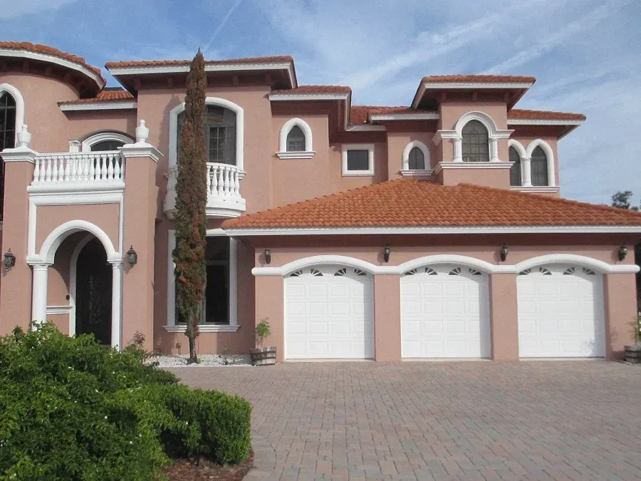 A large pink house with white garage doors