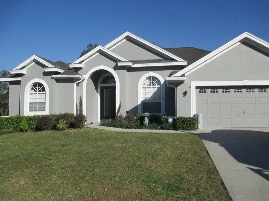 A gray house with a white trim and arched windows