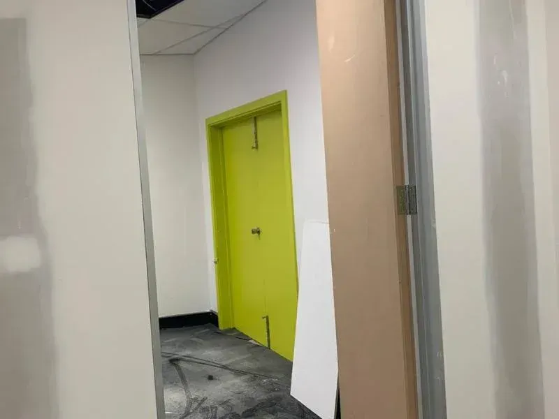 A hallway with a green door and a white wall.