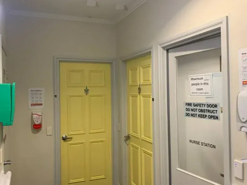 A hallway with yellow doors and a sign on the door that says `` fire safety door do not disturb do not keep open ''.