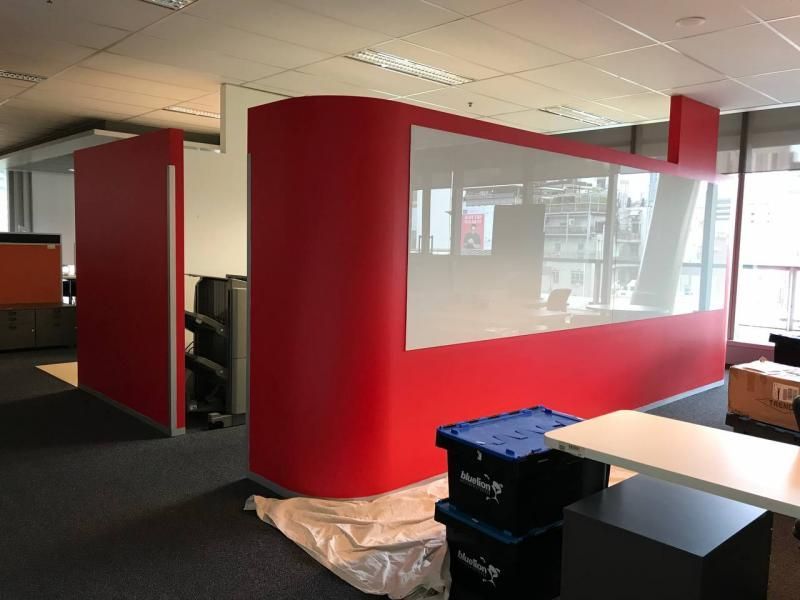 A room with a red wall and a white board on the wall.