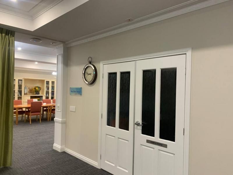 A hallway with a clock on the wall and a clock on the door.