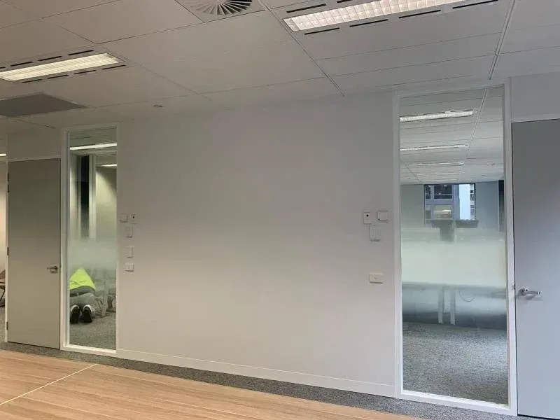 A large empty room with a wooden floor and a white wall.