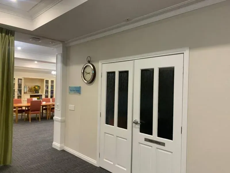 A hallway with a clock on the wall and a clock on the door.