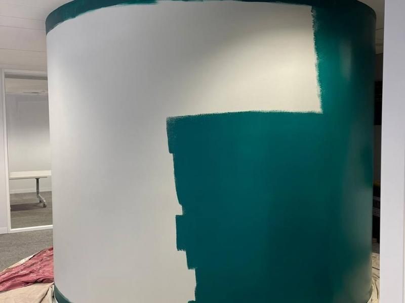 A green and white wall is being painted in a room.