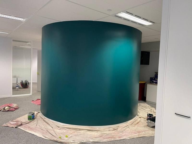 A large cylinder is being painted in a room.