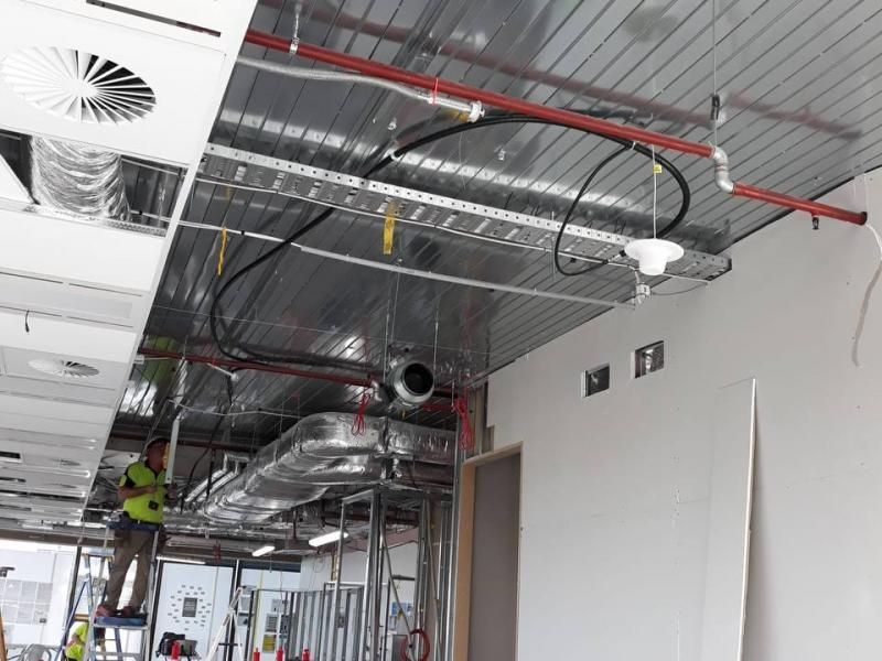 A man is working on the ceiling of a building.