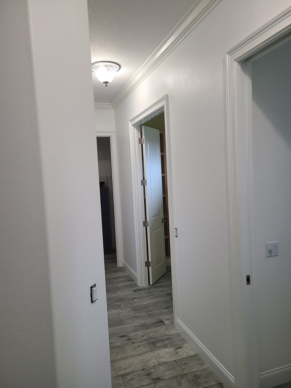 A hallway in a house with white walls and a door.