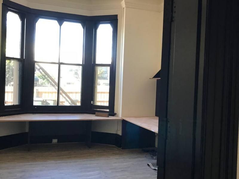 An empty room with a bay window and a desk