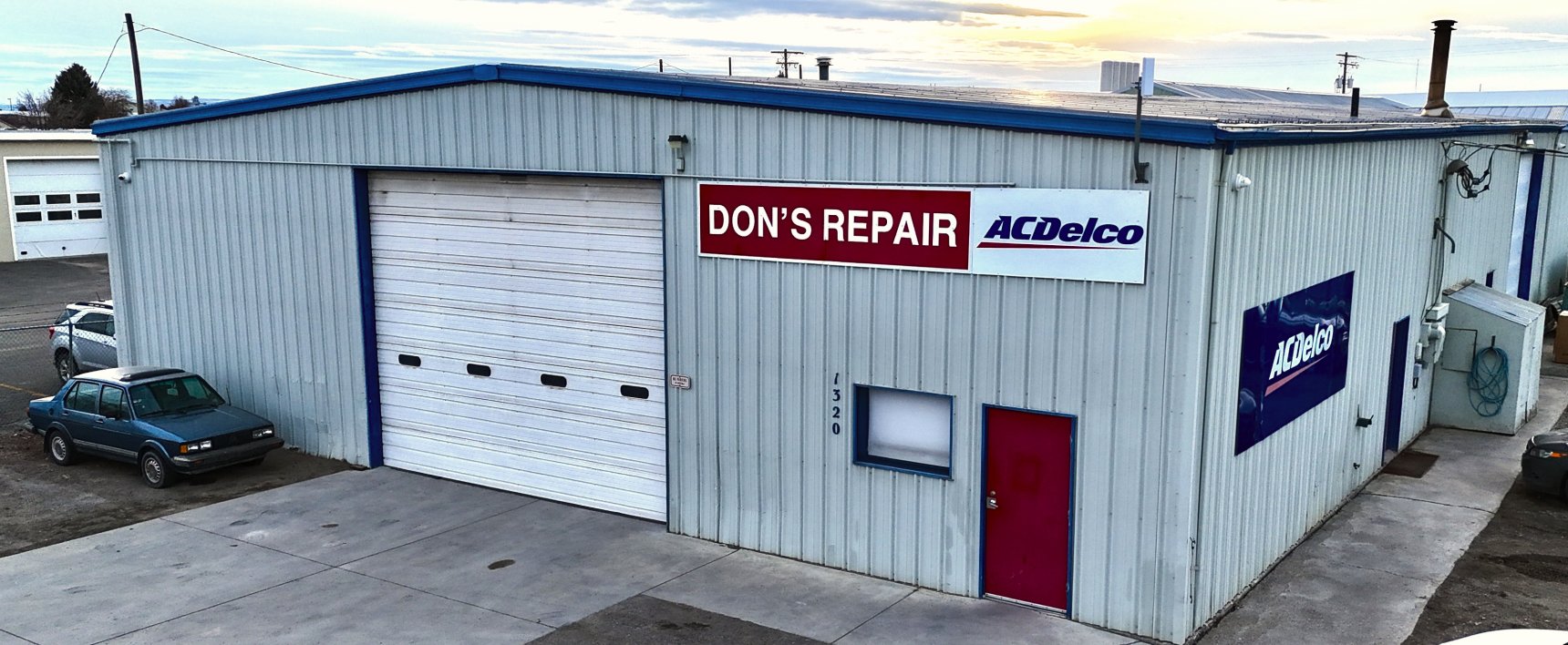 A group of six people posing for a photo in a garage. They wear matching work uniforms | Don's Repair