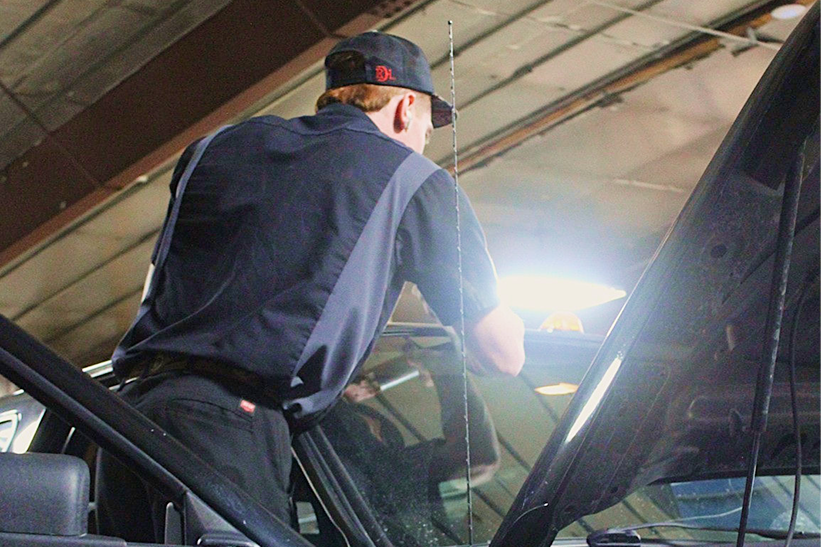 Tires stacked in a car repair shop; a vehicle is lifted on a hoist in the background | Don's Repair