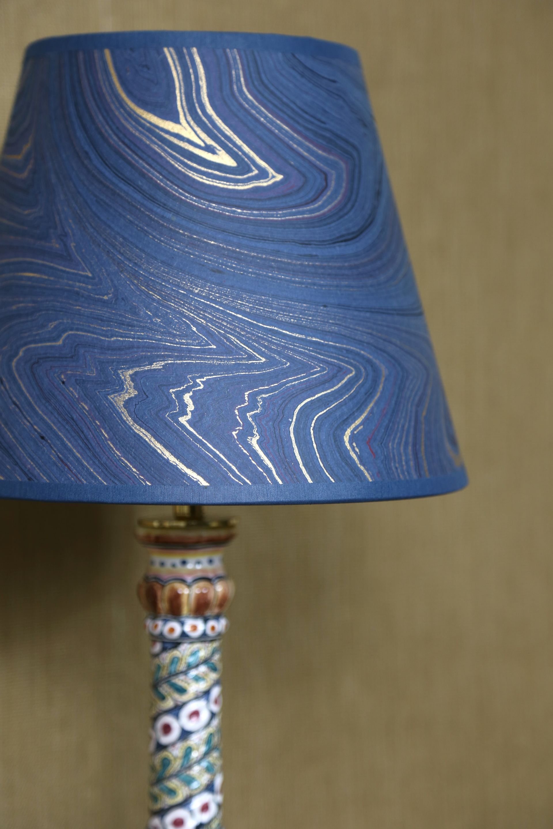 Lampenkap met blauw marmerpatroon op een decoratieve lampvoet met bloemmotief.