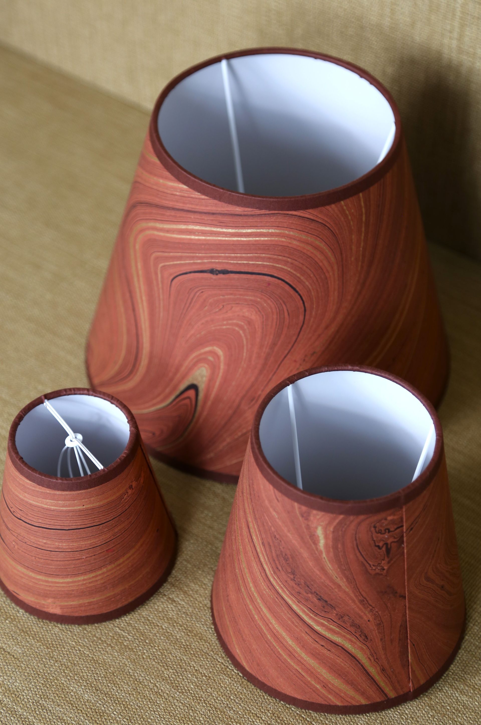 Terracotta kleurige lampenkap van hand gemarmerd papier met een witte binnenkant.