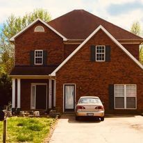 A brick house with a car parked in front of it.