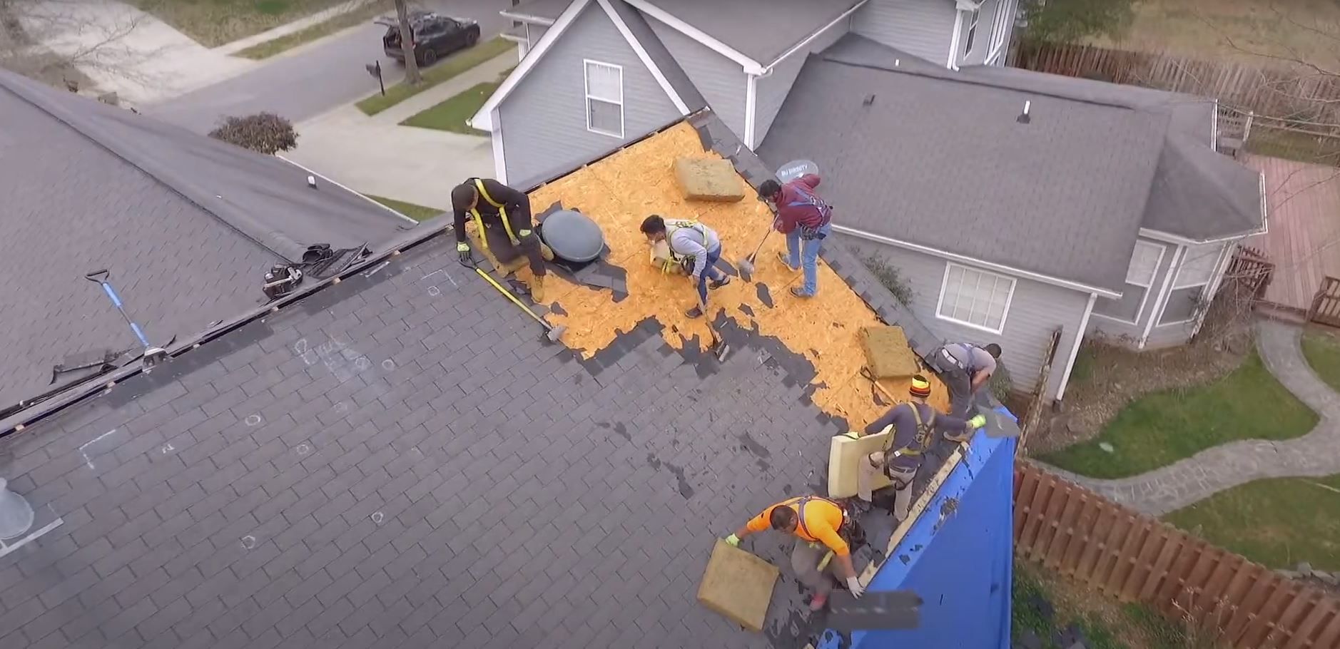 A group of people are working on the roof of a house.