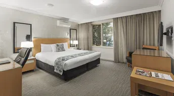 Hotel room with a bed, desk, window, and a television.