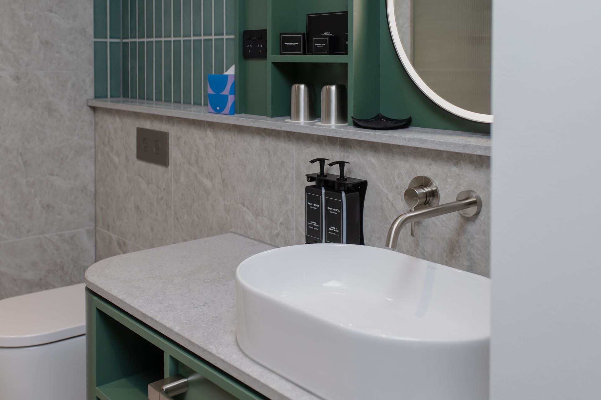 Modern bathroom with white sink, green accents, and a wall-mounted faucet.