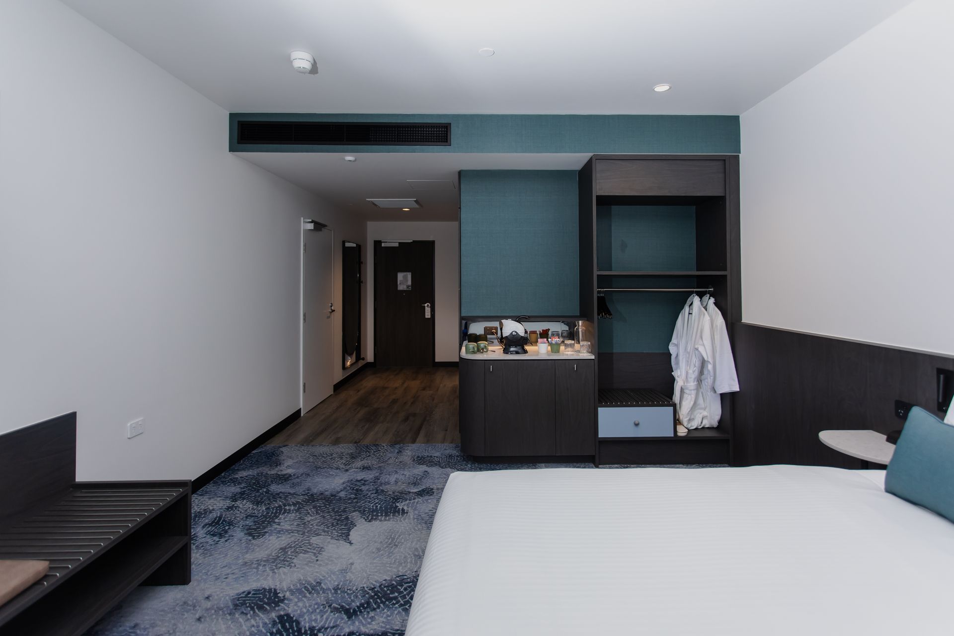 Hotel room with a bed, closet, and a desk with supplies.