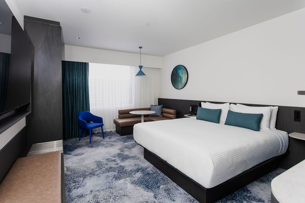 Hotel room with a king-size bed, seating area, and blue patterned carpet.