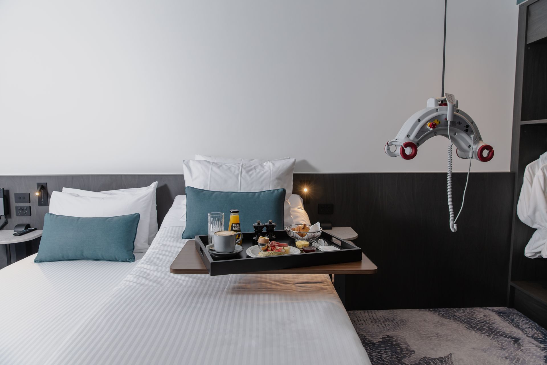 Hotel room with twin beds, breakfast tray, ceiling lift, and accessible features.