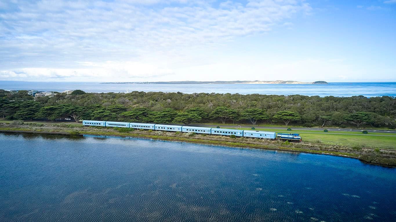 Overhead view of a coastline with a line of trailers between water and vegetation, under a cloudy sky.