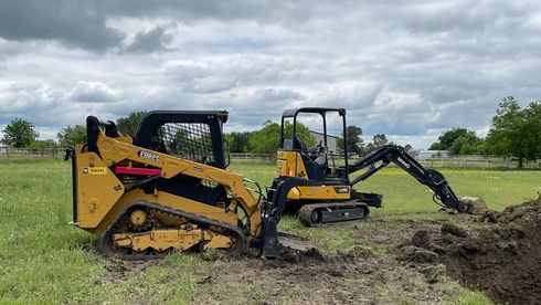 Mini excavator and track loader digging a hole in Roundrock, TX.