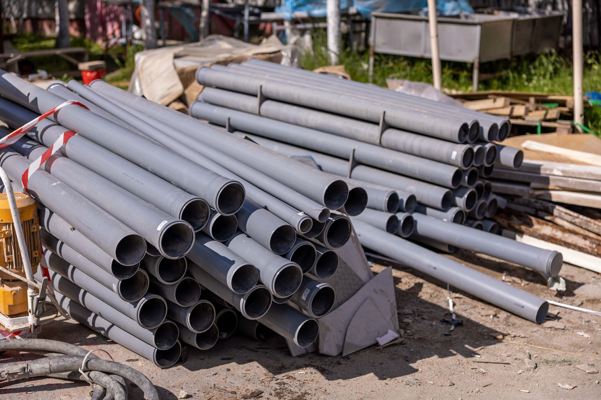 Stacked gray PVC pipes at an outdoor construction supply site