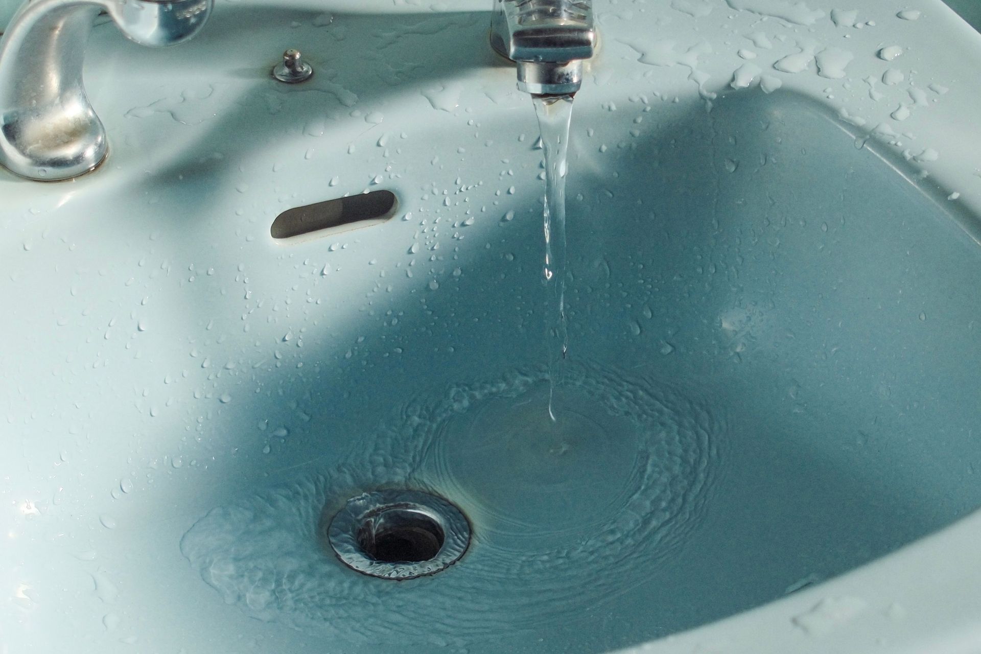Blue sink with running water flowing into the drain