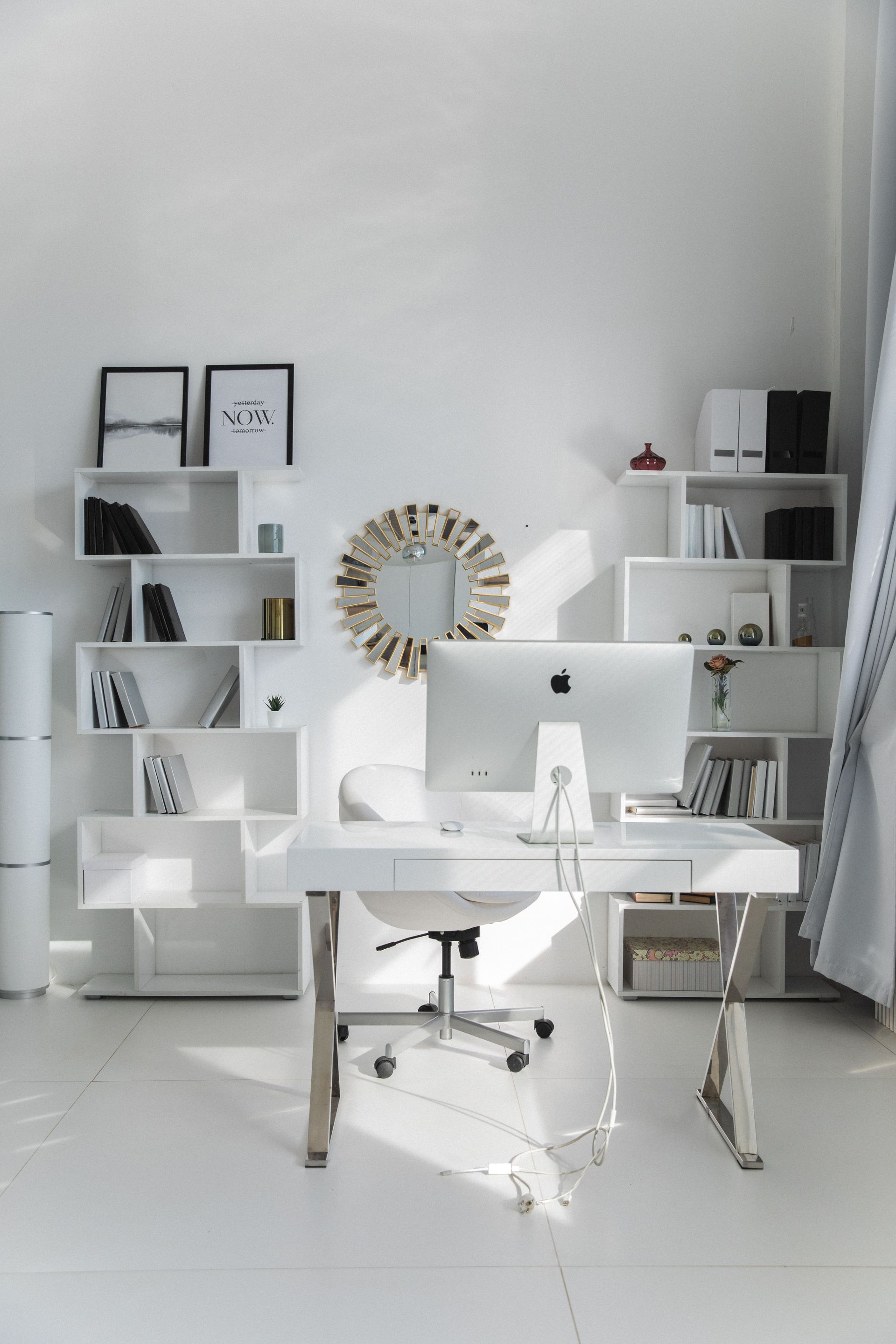 Bright white home office with desk, iMac, shelves, and a large wall mirror