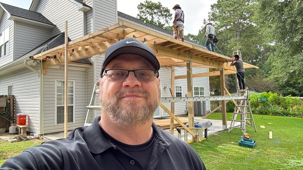 A man is taking a selfie in front of a house under construction.
