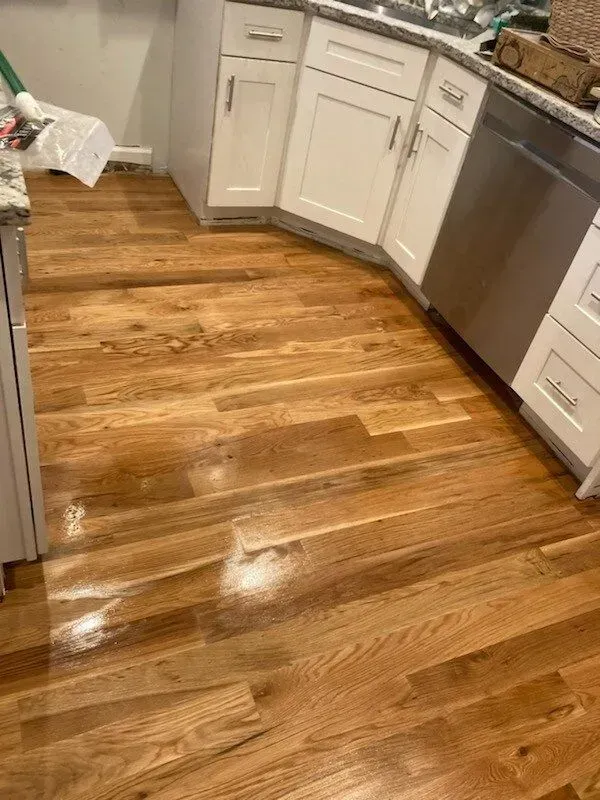 A kitchen with hardwood floors and white cabinets.