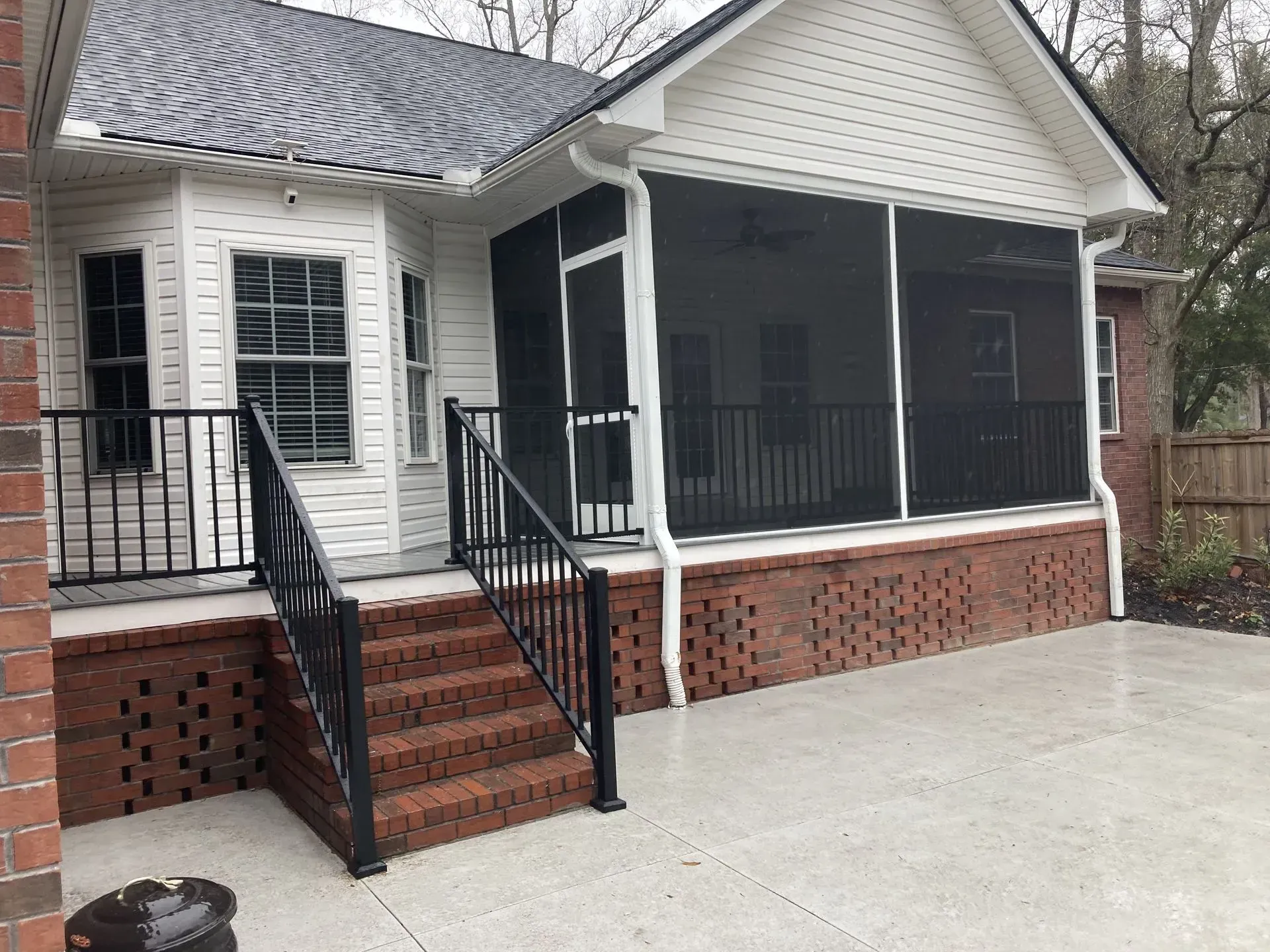 A white house with a screened in porch and stairs.