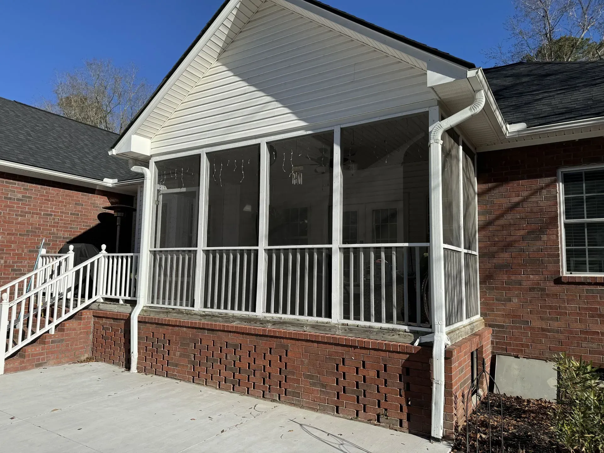 A screened in porch on the side of a brick house