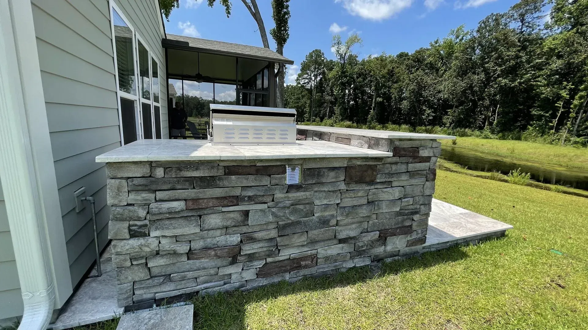 There is a stone wall in the backyard of a house.